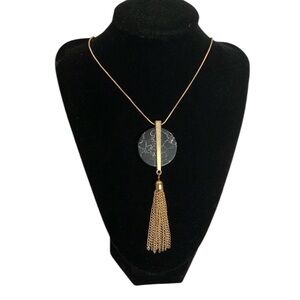 Long, gold tone necklace with stone medallion and tassel